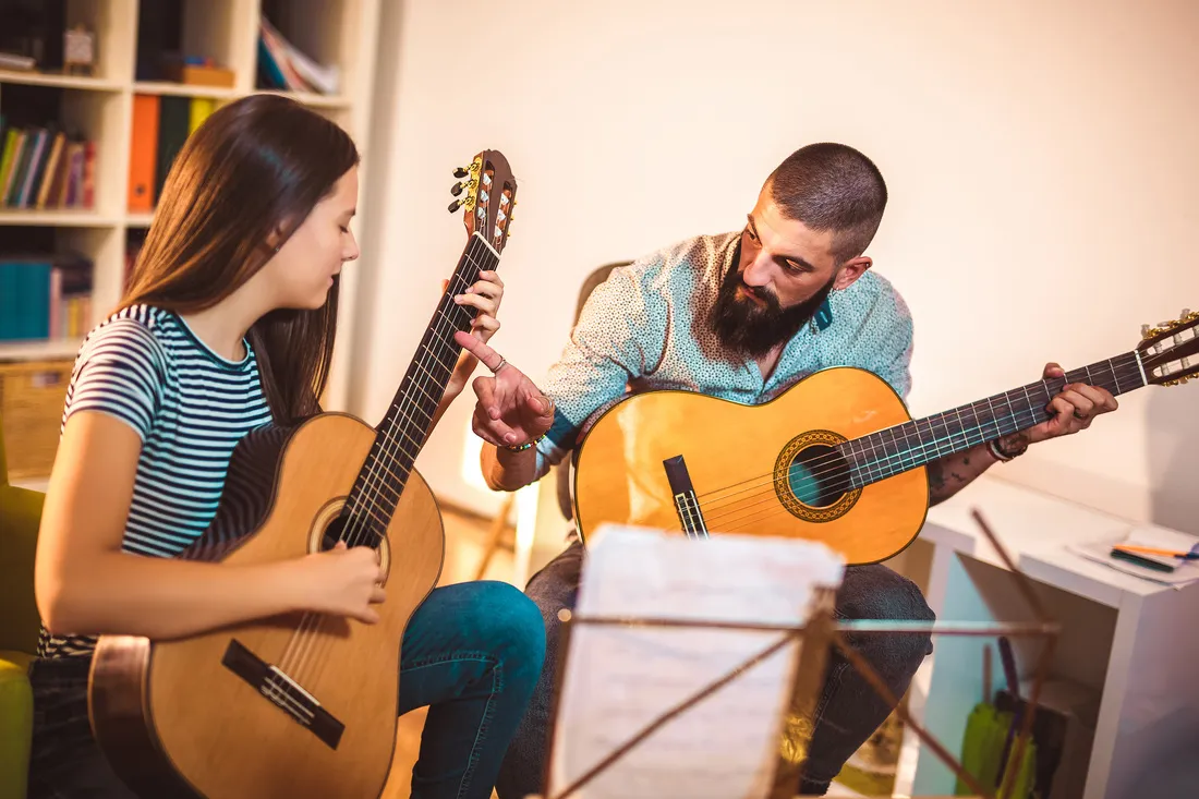  Gitarrenlehrer unterrichtet das Mädchen zu Hause.